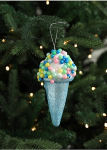 Blue glitter ice cream cone ornament hanging on a Christmas tree branch with warm bokeh