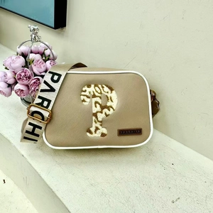 Chic khaki shoulder bag with PARCHITA lettering and gold P logo beside pink flowers