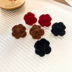 Macro view of velvet camellia stud earrings with double C logo in various autumn colors