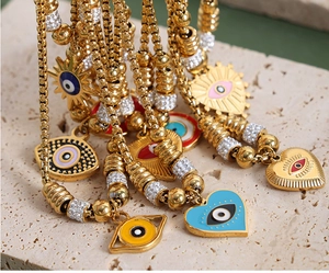 Detail of colorful evil eye pendants with 18K gold plating and zircon inlay on a stone edge