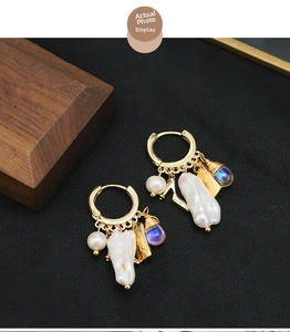Detail of gold hoop earrings with Baroque pearl, Love tag and blue pendant charm