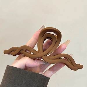 Dettaglio di pinza per capelli marrone opaco con design a onde incrociate