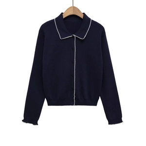 Detail of dark blue knit cardigan with white scalloped trim on wooden hanger