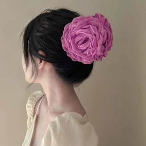 Detail of a large magenta rose fabric hair claw clip worn on a model for hair styling