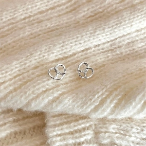 Macro shot of silver pretzel knot earrings with white zircons on soft knit fabric