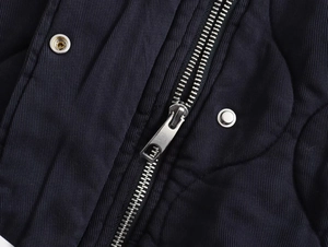 Macro shot of silver metal zipper and snap buttons on dark blue diagonal twill jacket