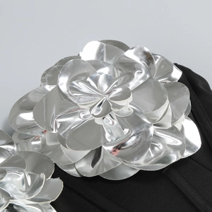Macro shot of large 3D silver metallic flower applique on a black evening gown detail