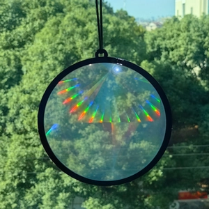 Detail of a round holographic suncatcher with black frame reflecting rainbow light
