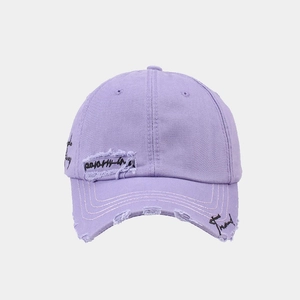 Detail of light purple vintage baseball cap featuring distressed rips and graffiti embroidery