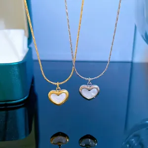 Close-up of gold and silver heart necklaces with white mother of pearl on jewelry box