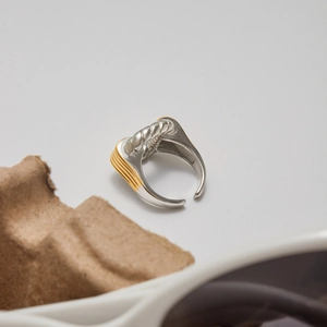 Détail macro d'une bague bicolore argent et or en acier inoxydable sur fond de papier