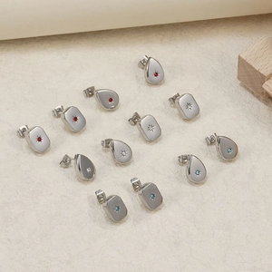 Macro detail of silver stainless steel stud earrings with colorful zircon star settings