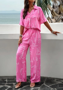 Detail of pink floral short sleeve shirt and trousers set with white line art patterns
