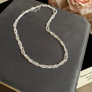 Detail of double-layer woven necklace with white pearls and silver twist chain
