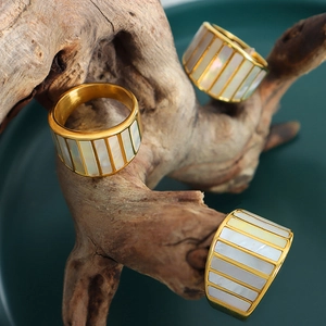 Three gold rings with rectangular white shell inlays on a natural wood branch