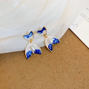 Vue macro de boucles d'oreilles fleur émail bleu avec perle et bordure dorée