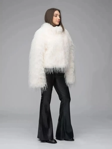 Close-up of white faux fur coat paired with black satin flared trousers for women