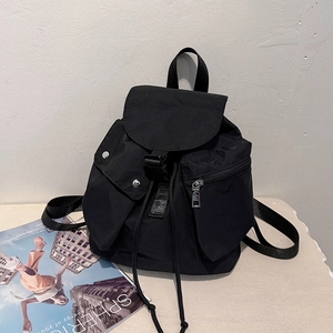 Detail of black nylon backpack with drawstring closure, flap cover and front pockets