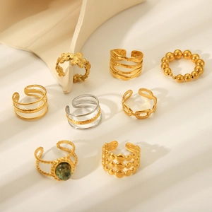 Flat lay of gold and silver stainless steel rings set with green stones and textures