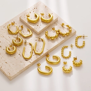 Minimalist gold plated titanium steel earring set on travertine stone display