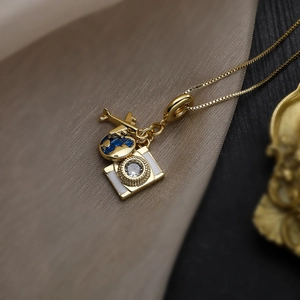 Gold travel theme necklace with airplane globe and camera charms on gold box chain