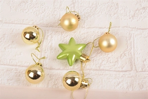 Detail of gold baubles and green star ornament on textured white decorative board