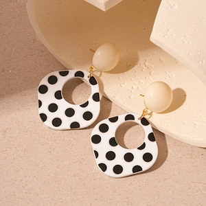 Detailed view of geometric acrylic earrings with black and white polka dot patterns