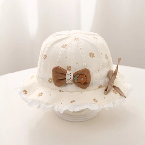 Detail of baby sun hat with brown bow, floral print and white lace trim edging
