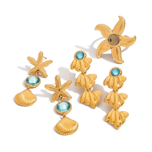 Golden starfish and shell jewelry set with blue and gray gemstones on white background