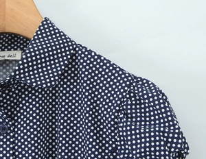 Close-up of navy blue shirt collar with white polka dots on a wooden hanger