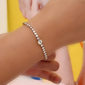 Close-up of a gold chain bracelet featuring round white zircon stones on a model's wrist