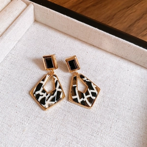 Détail des boucles d'oreilles géométriques imprimé léopard avec bordure dorée chic