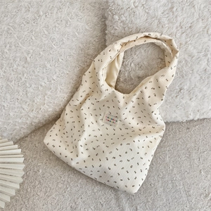 Gros plan sur le sac fourre-tout en velours côtelé beige à imprimé floral et étiquette