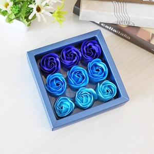 Close-up of 9 blue soap roses arranged in a square gift box on a wooden surface