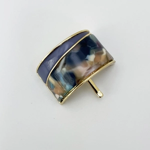 Detailed close-up of a resin ponytail cuff with gold metal frame and tortoise shell pattern