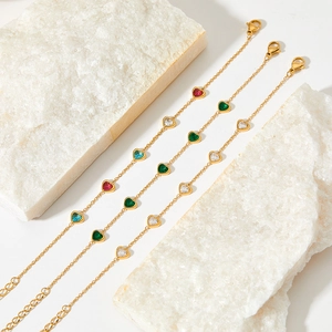 Three gold stainless steel heart bracelets with colorful zircon stones on white stone