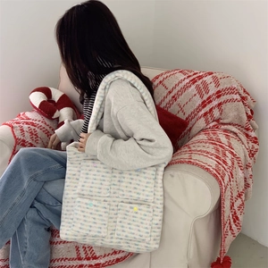Detail of colorful tweed tote bag with four front pockets held by a model in a cozy room