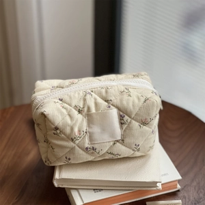 Close-up of quilted floral corduroy pouch with vintage label on a wooden desk
