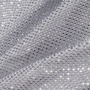 Détail macro du tissu argenté avec des strass scintillants et texture métallique