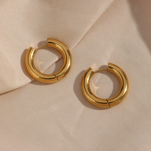 Polished 18K gold chunky hoop earrings on elegant champagne silk fabric background