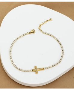 Detail of gold cross bracelet featuring sparkling cubic zirconia on a tennis chain
