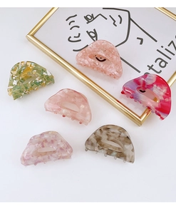 Variety of semi-circular acetate hair claws in marble and floral patterns on white background