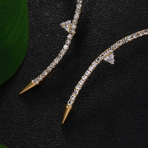 Golden rhinestone necklace with triangular crystals and metallic spikes on dark background