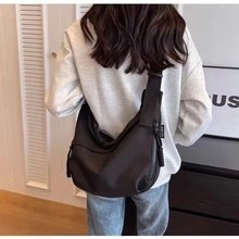 Vista trasera detallada de un bolso bandolera negro que muestra la capacidad y el ajuste real