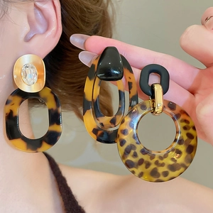 Detail view of large leopard print acrylic hoop earrings with rhinestones and metal accents