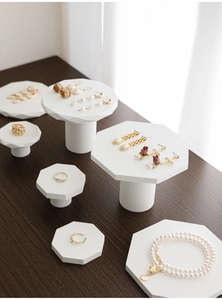 Detailansicht von goldenem Ohrschmuck und Perlenkette auf achteckigem Schmuckständer