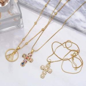 Detailed view of three gold-plated religious necklaces with colorful zircon crosses and Virgin Mary