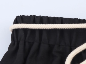 Dettaglio vita elastica con coulisse in cotone beige sui pantaloni ricamati neri
