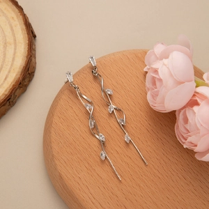 Detailed shot of silver leaf tassel earrings with sparkling cubic zirconia on wood