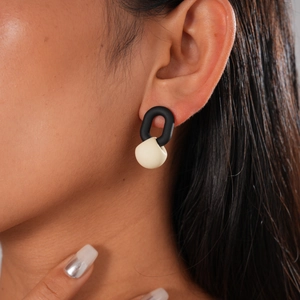 Nahaufnahme von minimalistischen schwarz-beigen U-Ohrringen mit mattem Finish am Model